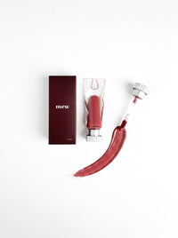 mew lip glaze in Deer Blood beside its carton, with a brick red swatch